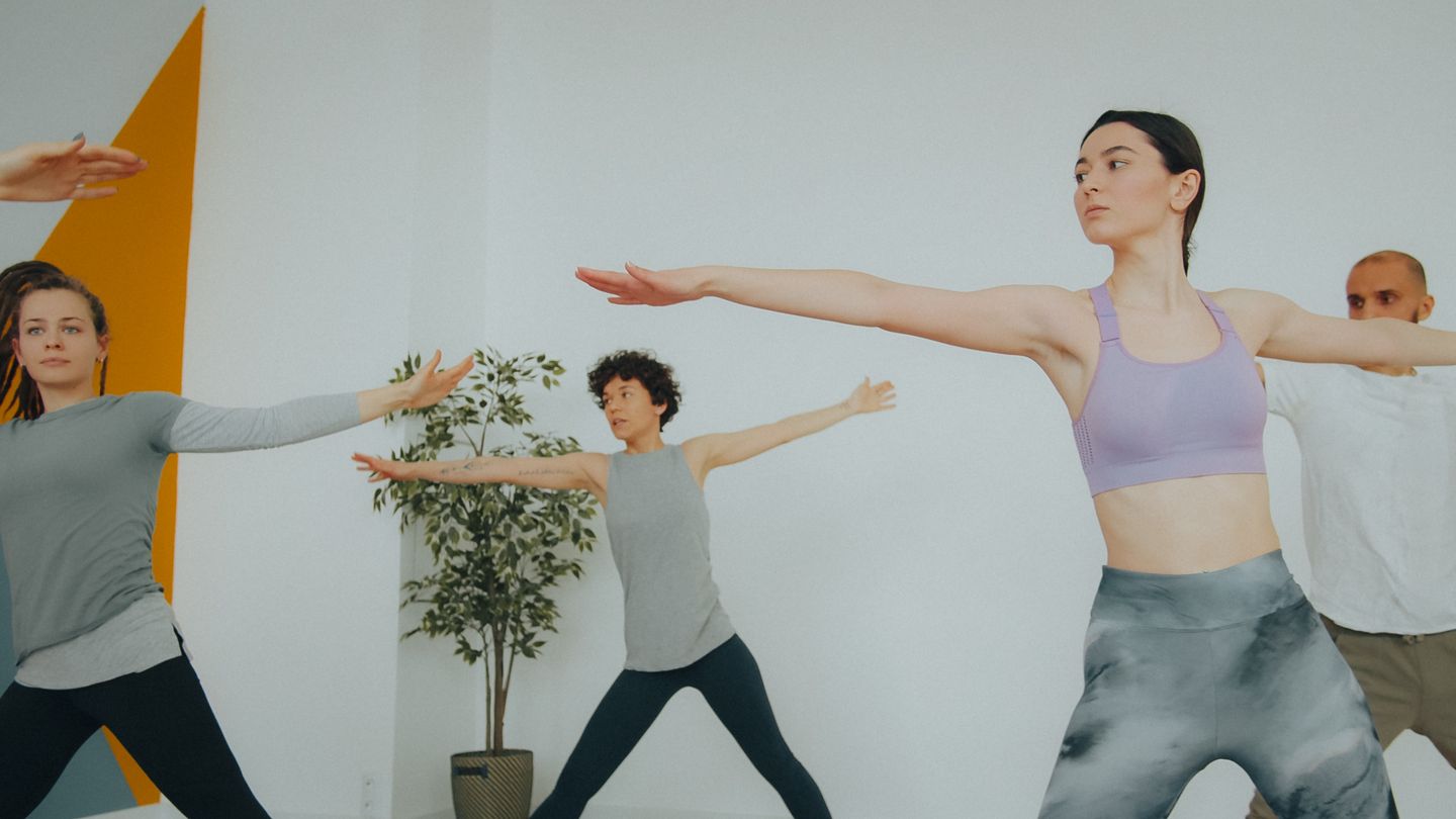 Diverse group of adults practicing yoga in a modern indoor studio environment.